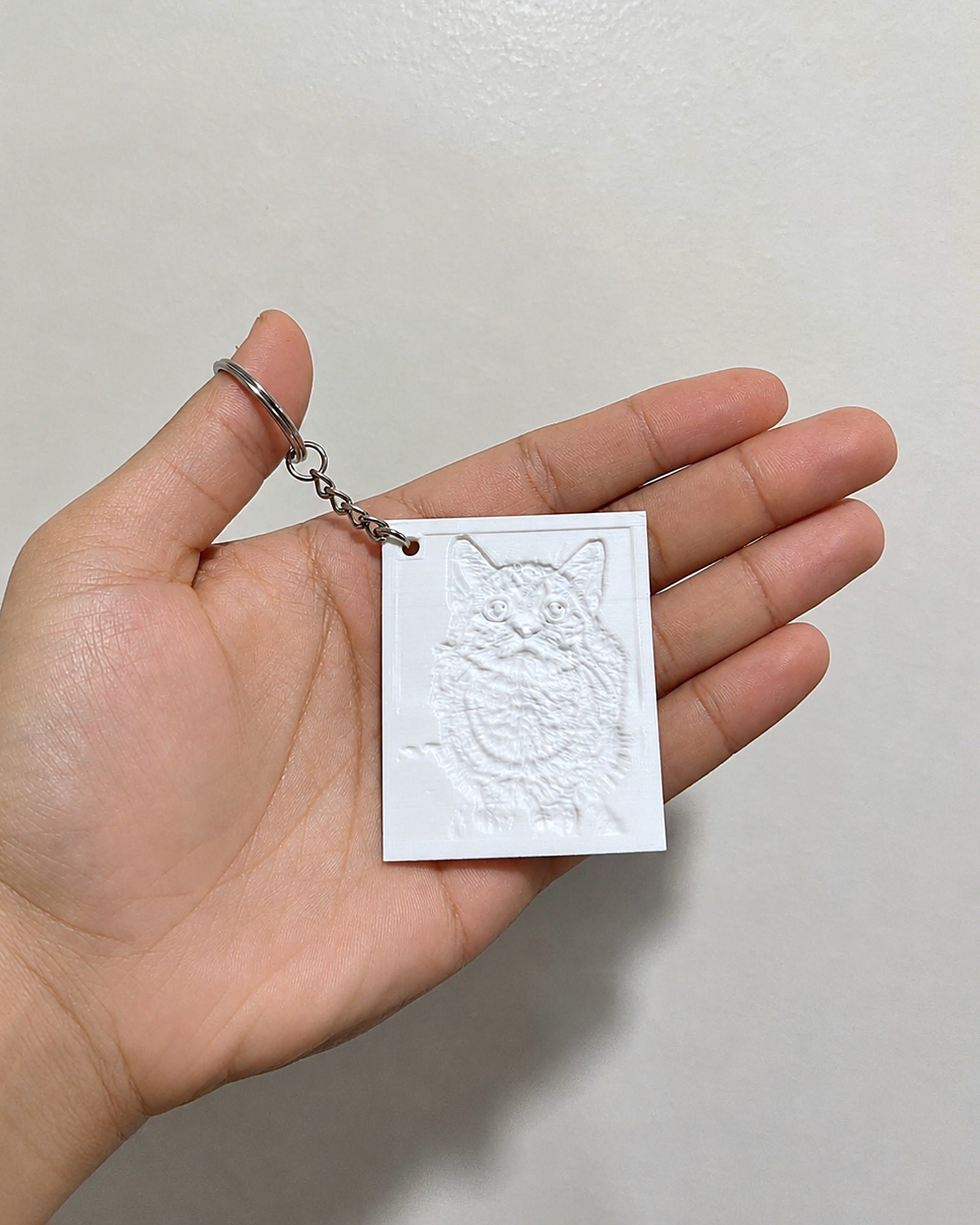 Small lithophane pet keychain resting in an open palm to show its size